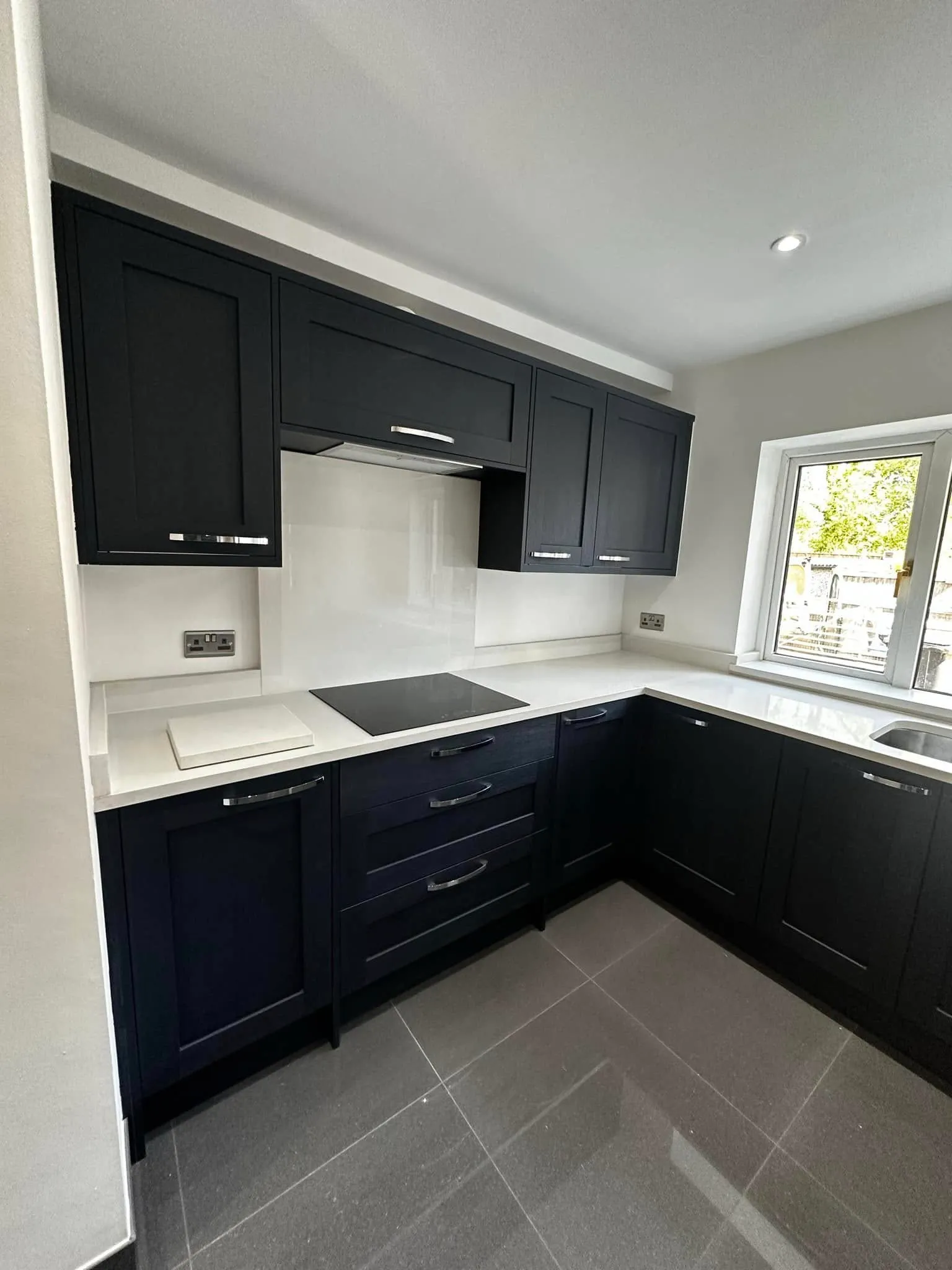 The hob wall of the graphite shaker kitchen with white quartz worktops
