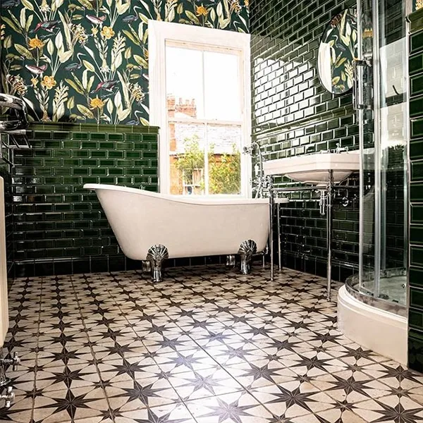 Victorian-style bathroom with racing-green metro tiling, botanical wallpaper and a white roll-top slipper bath on chrome claw feet