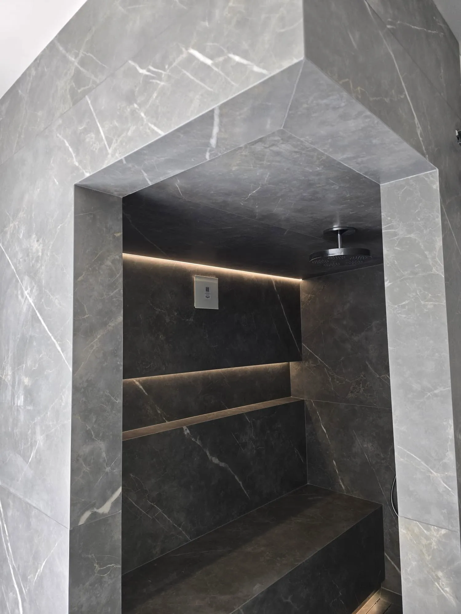 Faceted grey marble archway looking into the lit steam room
