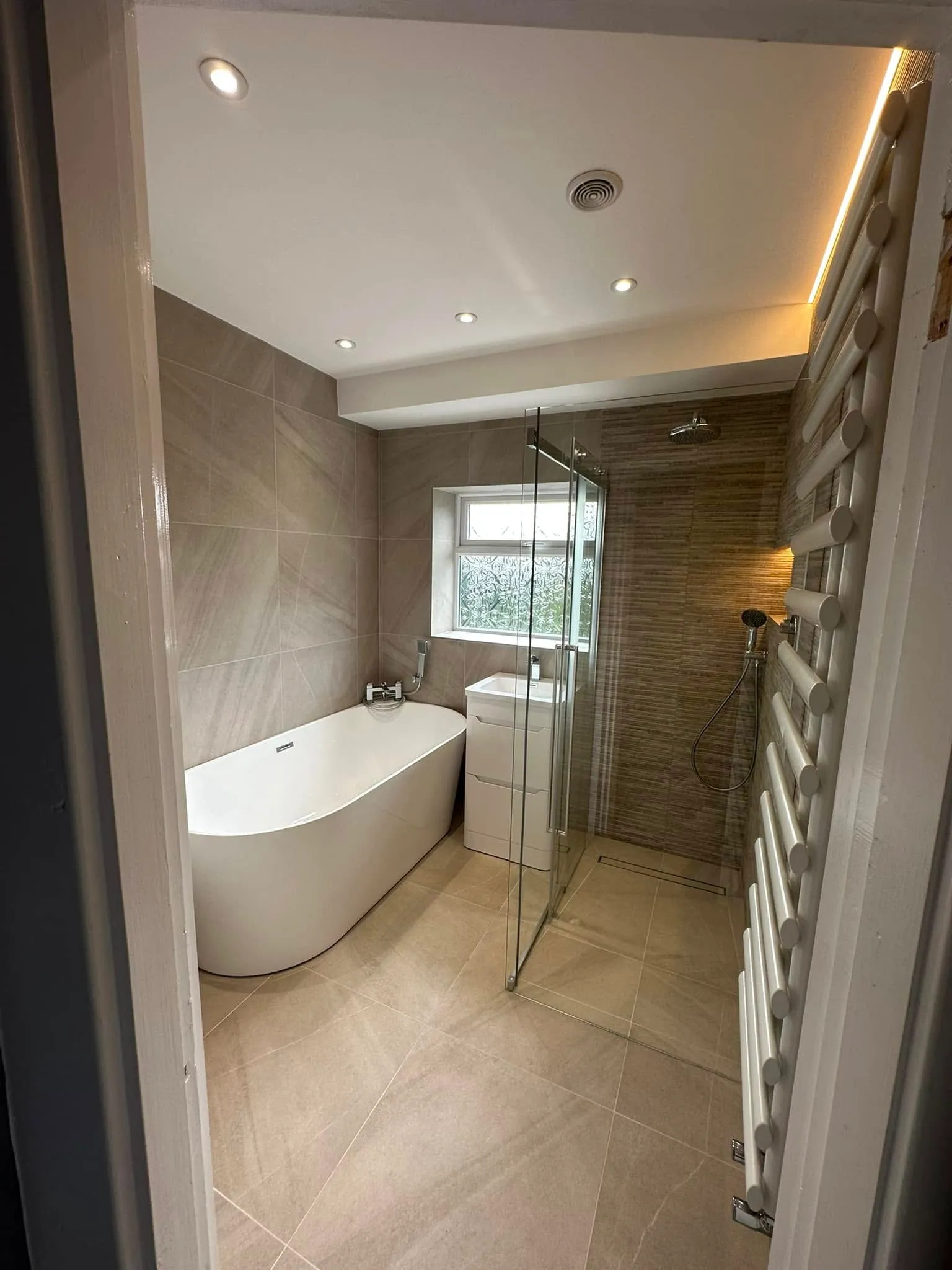 Doorway view of the whole suite: bath, vanity, shower and glowing LED cove
