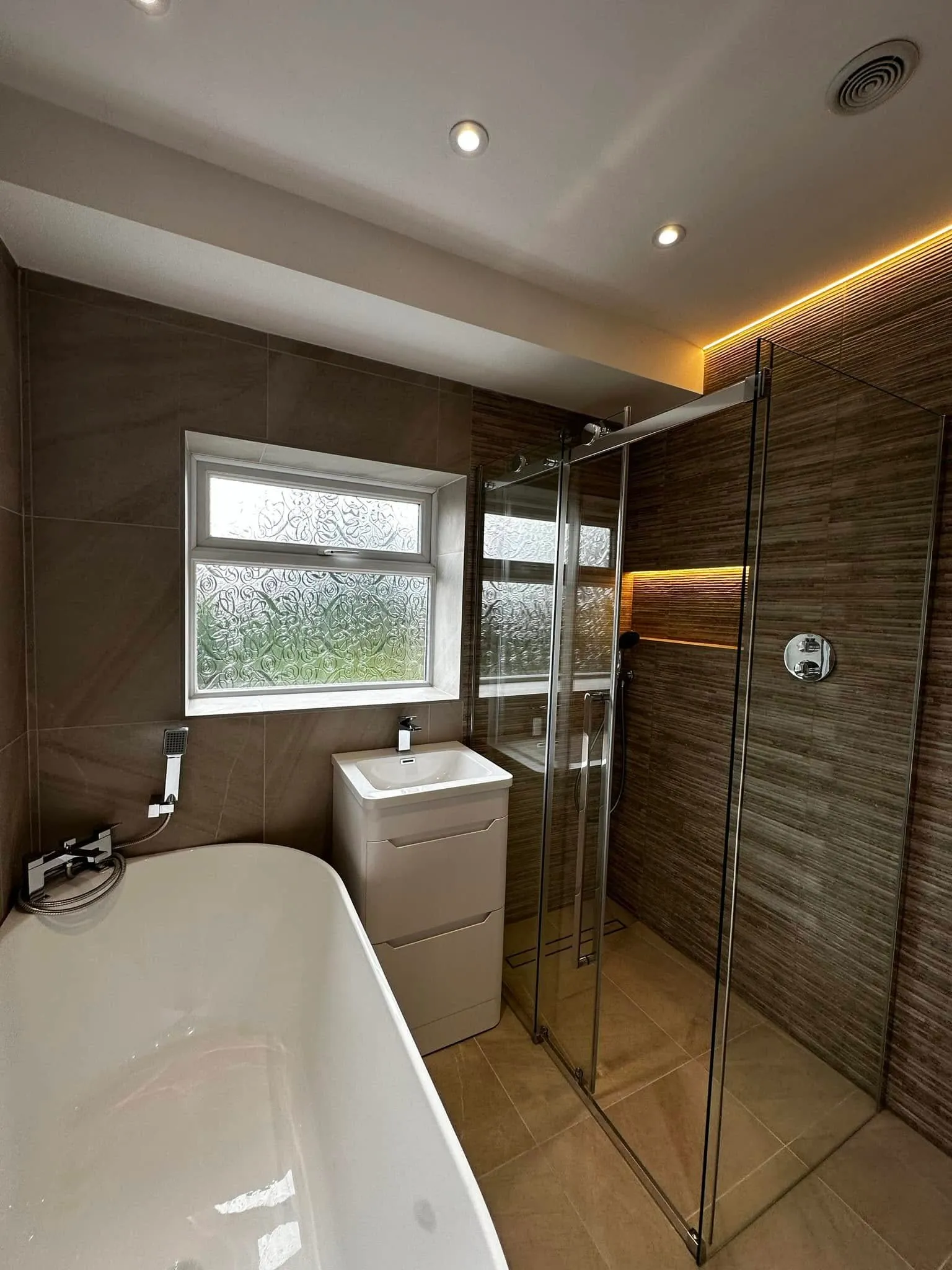 Freestanding bath by the window with the walk-in shower beyond
