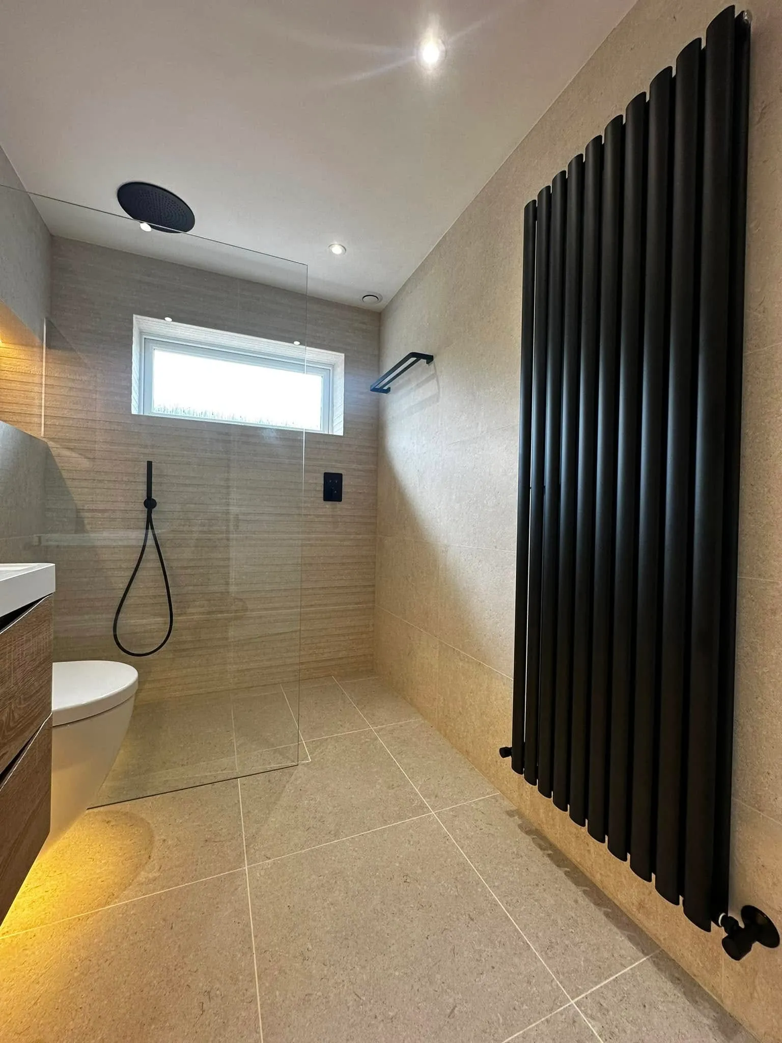 Shower wall with matt black rainhead and tall black radiator