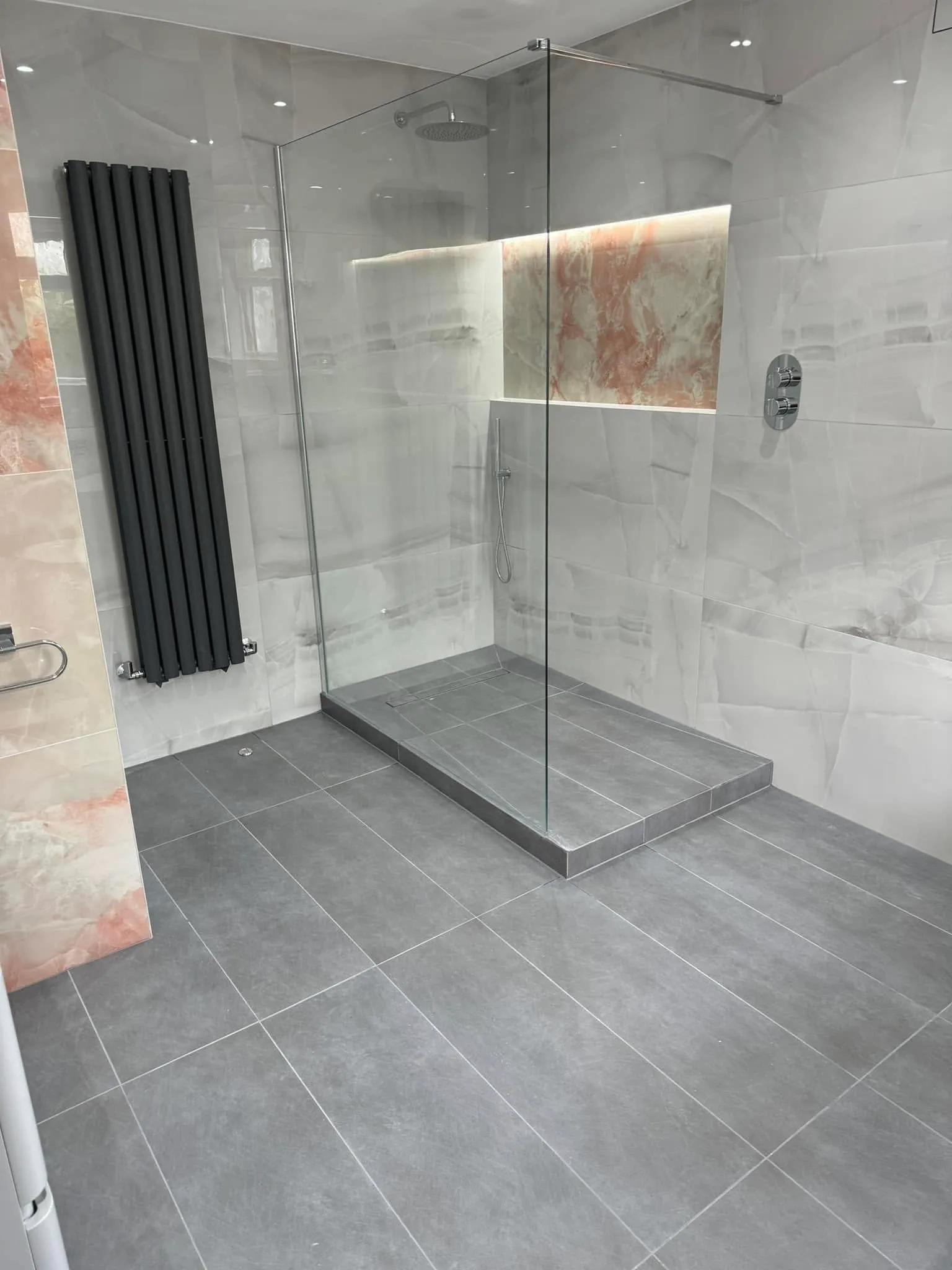 Walk-in shower with blush onyx niche and anthracite radiator