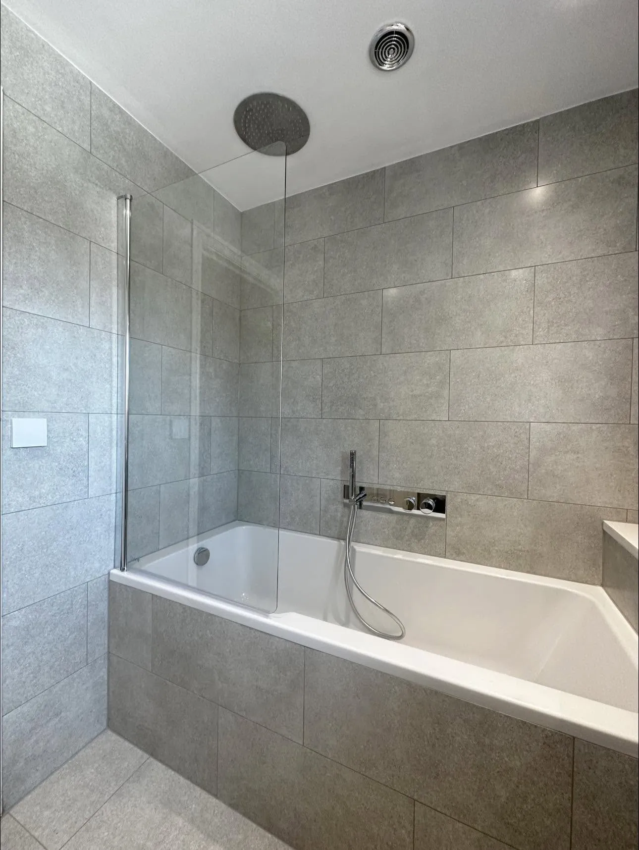 Bath with ceiling-recessed rainhead and glass screen