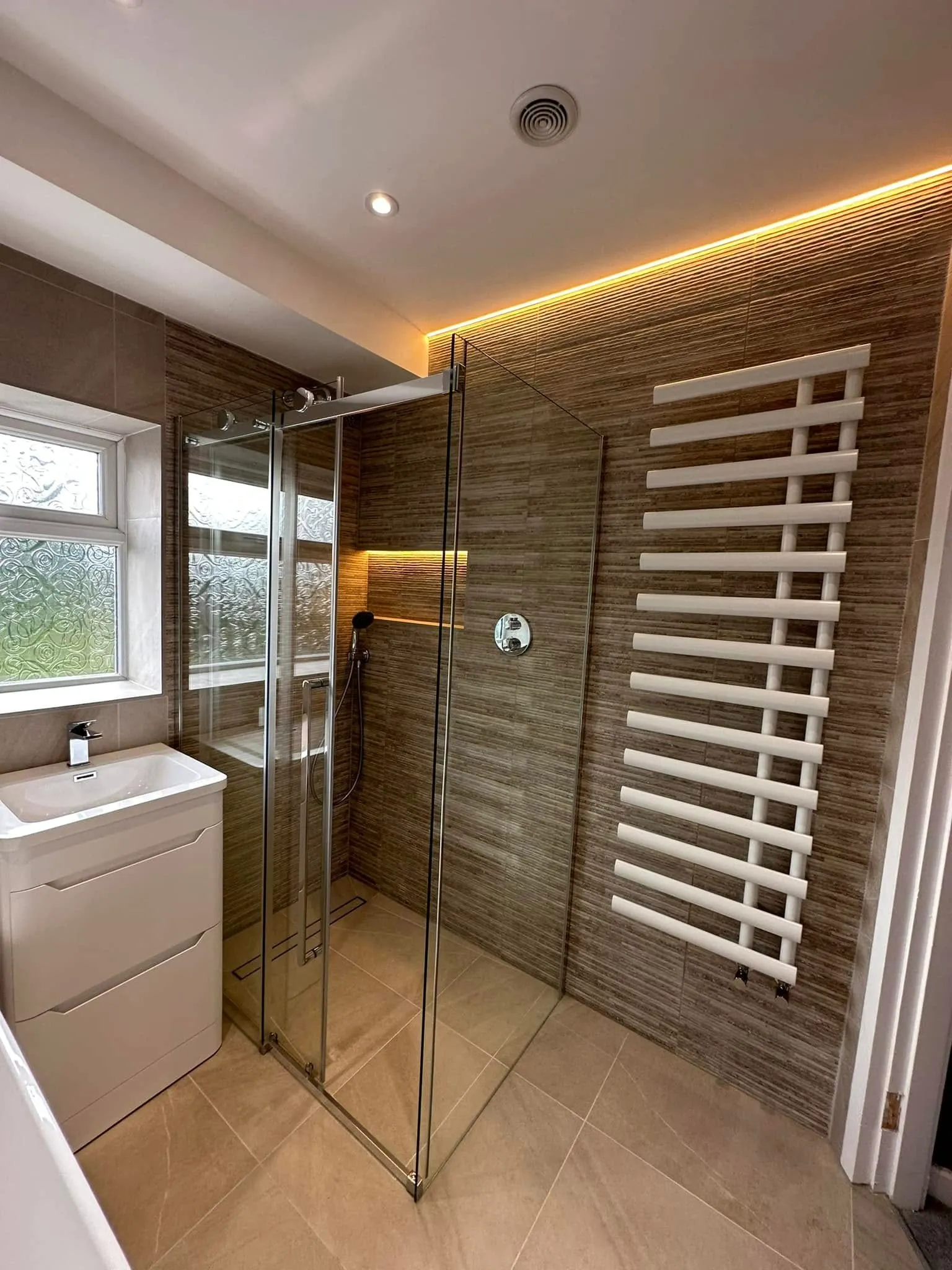 Frameless sliding shower enclosure and white designer towel radiator