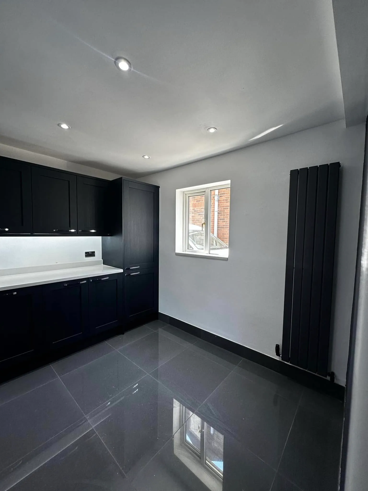 Black feature wall with vertical radiator and lit splashback