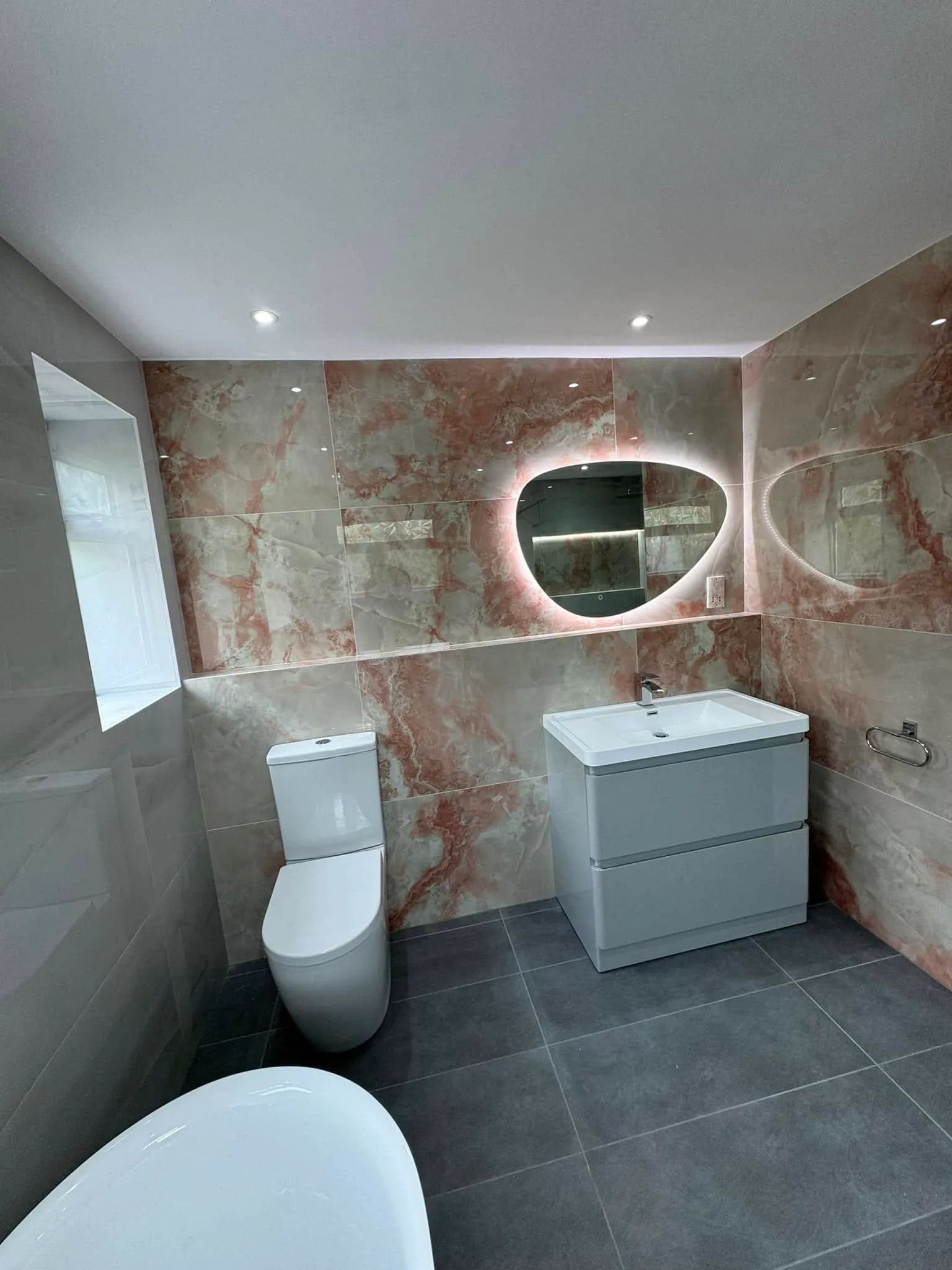 White gloss vanity, WC and backlit pebble-shaped mirror