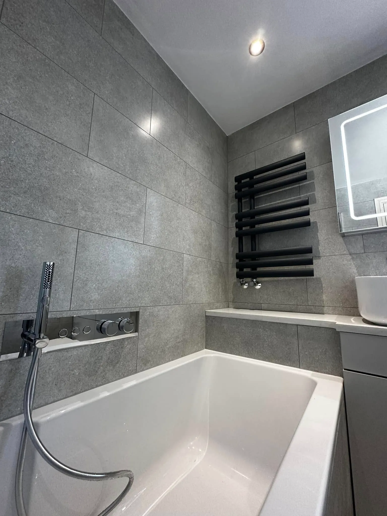 Corner view of bath, radiator, mirror and vanity