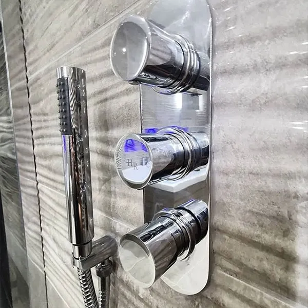Triple-control concealed thermostatic shower valve in chrome on grey stone-effect tiling
