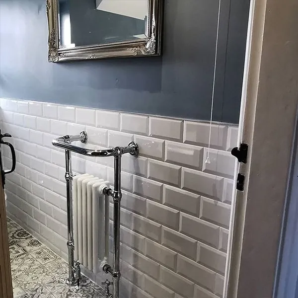 Traditional chrome and white towel radiator against bevelled metro tiling and slate-blue walls