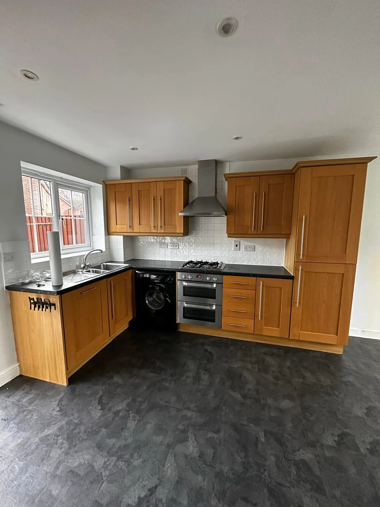 Oak shaker kitchen with black worktops, chimney extractor and gas hob